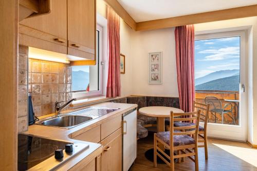 eine Küche mit einem Waschbecken, einem Tisch und einem Fenster in der Unterkunft Apt Eisacktal in Meransen