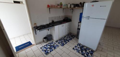 a kitchen with a white refrigerator and a tiled floor at Apartamento Guriri Verão in São Mateus