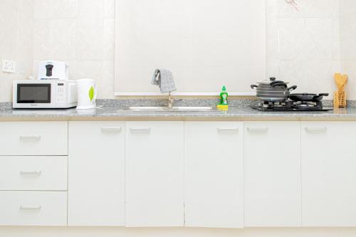 a white kitchen with a microwave and a stove at Novara Apartments in Lekki