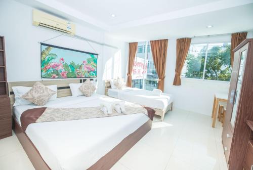 a white room with two beds and a tv at Happy 99 Guest house in Patong Beach