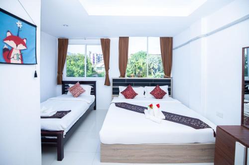two beds in a room with two windows at Happy 99 Guest house in Patong Beach