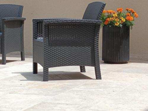 a black wicker chair sitting next to a vase of flowers at L'étoile de Zakiel in Cambayrac