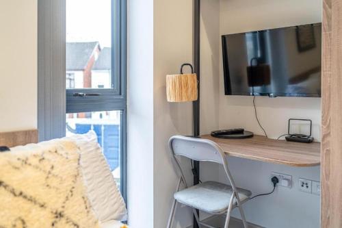 a room with a desk with a television and a chair at Stylish Studio Apartment with Free Parking in Wolverhampton 5min walk to City Centre in Wolverhampton