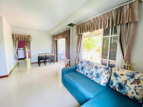 a blue couch in a living room with a window at baan sugaiyah in Phra Ae beach