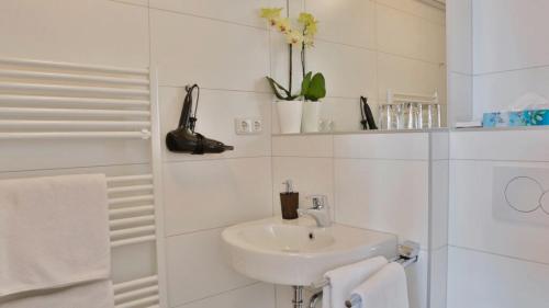ein weißes Bad mit einem Waschbecken und einer Dusche in der Unterkunft Das Falk Apartmenthaus in Nürnberg
