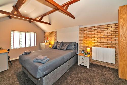 Finest Retreats - Chocolate Box Cottage في Potton: غرفة نوم بسرير وجدار من الطوب