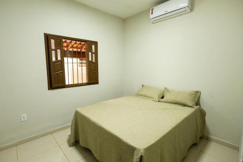 a small bedroom with a bed and a window at Casa Temporada Guriri Pé na areia! in São Mateus