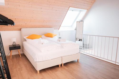 1 dormitorio con 1 cama blanca grande con almohadas de color naranja en Maisonette-Wohnung Airport/Messe Stuttgart - Balkon - Parkplatz - Netflix en Filderstadt