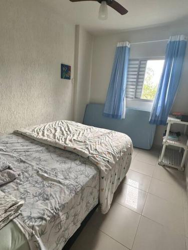 een slaapkamer met 2 bedden en een raam met blauwe gordijnen bij Apto no centro de Bertioga in Bertioga
