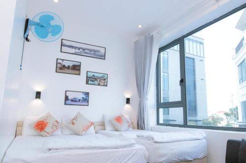 トゥイホアにあるThành Tính Hotel - Khách sạn Phú Yênの大きな窓付きの客室で、白いベッド2台が備わります。