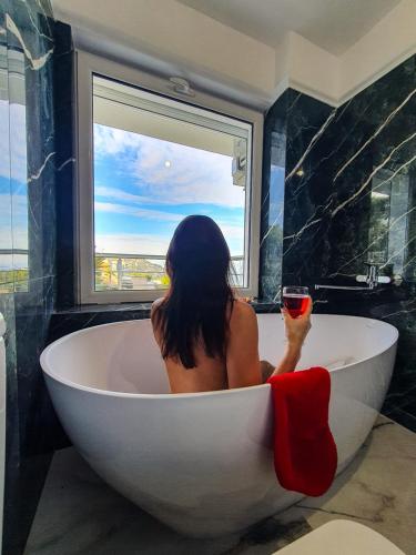 a woman sitting in a bath tub holding a glass of wine at PIOTROWSKI APARTMENTS in Theológos