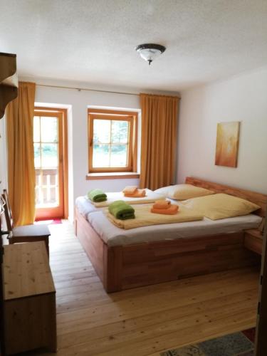 a bedroom with a large bed and two windows at Alpengasthof Gutenbrunn in Mallnitz