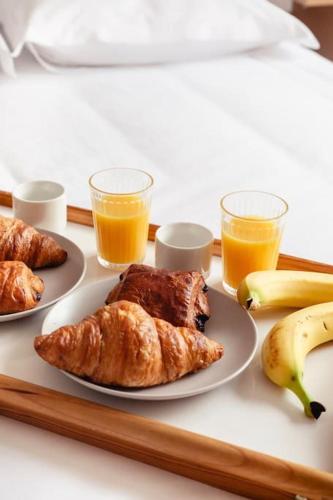 a tray with two plates of food and two glasses of orange juice at LA BELLE ROSE - Appartement 4 personnes proche gare Bordeaux in Bègles