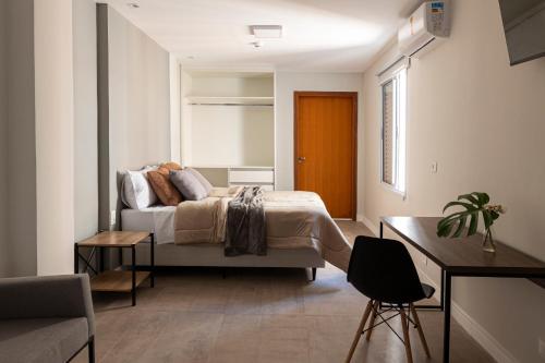 um quarto com uma cama, uma mesa e uma cadeira em CoVívere em São Paulo