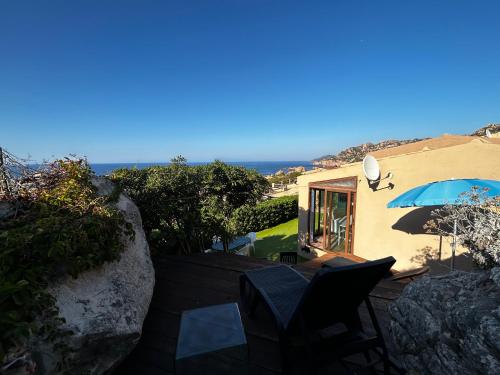 a house with a balcony with a blue umbrella at Casa Li Cossi vicino al mare in Costa Paradiso