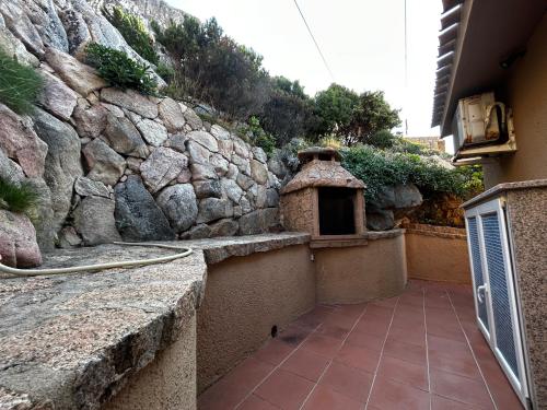 a stone wall next to a building with a fireplace at Casa Li Cossi vicino al mare in Costa Paradiso