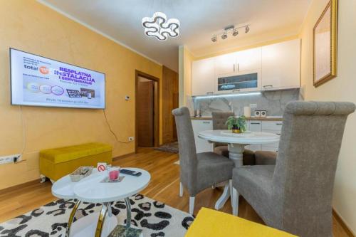 a living room with two tables and a kitchen at Apartman Grand Zlatibor in Zlatibor