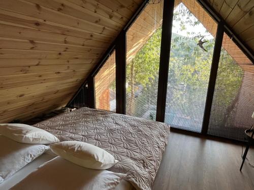 a bedroom with a bed in a room with large windows at Parádka - Toscana Villa in Parád