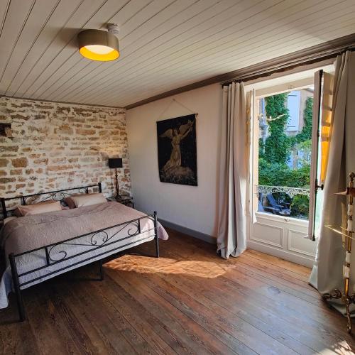 a bedroom with a bed and a large window at Tourellerenard in Bussières-lès-Belmont