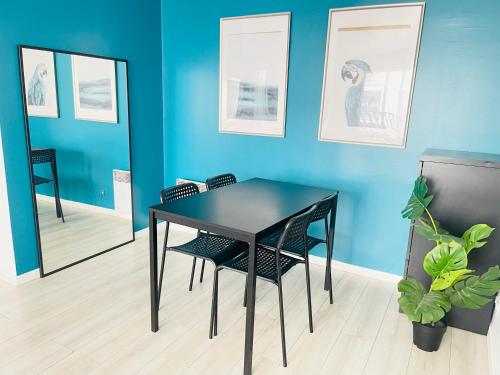 Cosy appart proche Paris في سان دوني: طاولة سوداء وكراسي في غرفة ذات جدار أزرق