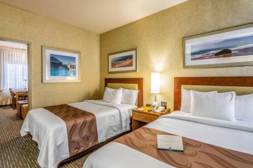 サンルイス・オビスポにあるQuality Suites Downtown San Luis Obispoのベッド2台とデスクが備わるホテルルームです。