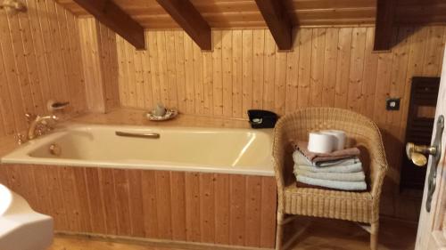 a bathroom with a tub and a chair with towels at Ferienwohnung in Mörlenbach