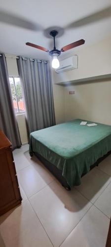 1 dormitorio con cama verde y ventilador de techo en Apto a 300mt da Praia do Forte, Cabo Frio. RJ. en Cabo Frío