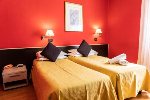 two beds in a room with red walls at Hotel Berlino in Milan