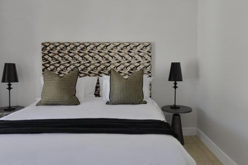 a bedroom with a large white bed with two lamps at Fransvliet Guest House in Franschhoek