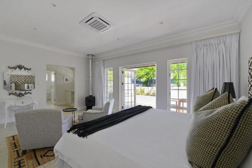 a white bedroom with a large bed and a balcony at Fransvliet Guest House in Franschhoek