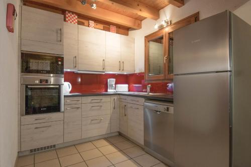 La cuisine est équipée de placards blancs et d'un réfrigérateur en acier inoxydable. dans l'établissement Chalet Portes du Soleil 1, aux Gets