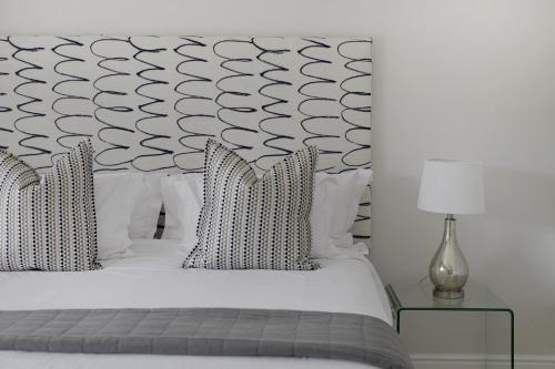 a bedroom with a white bed with a black and white headboard at Fransvliet Guest House in Franschhoek