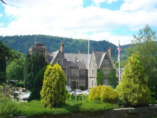 a large house with trees in front of it at Maenan Abbey Hotel in Llanrwst