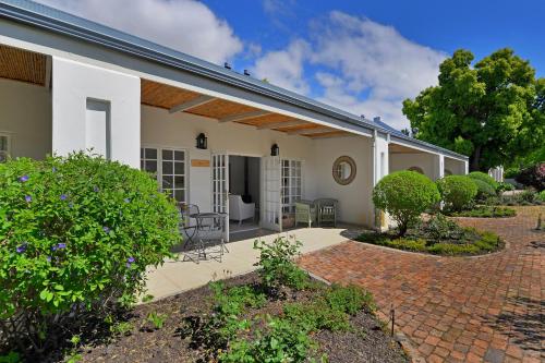 a patio of a house with bushes and trees at Fransvliet Guest House in Franschhoek