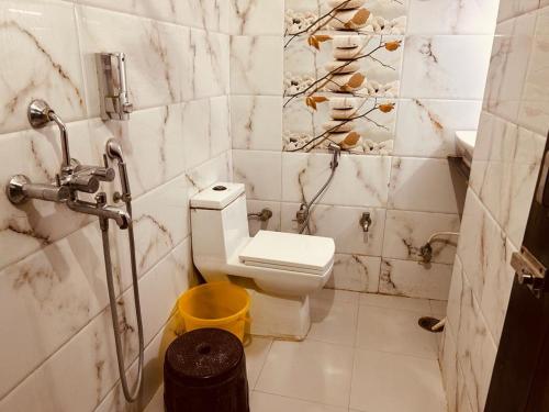 a bathroom with a toilet and a yellow trash can at The For You Hotel & Restaurant in Rishīkesh