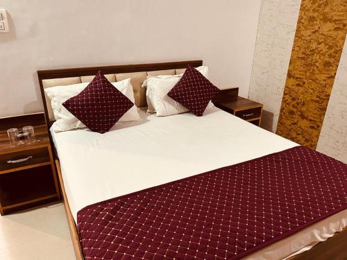 ein großes Bett mit roter und weißer Bettwäsche und Kissen in der Unterkunft The For You Hotel & Restaurant in Rishikesh