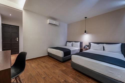 a hotel room with two beds and a table at Hotel Mexico, Merida in Mérida