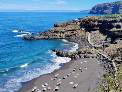 una playa con sombrillas y gente en la playa en Casa Rural - Playa. Situada en un entorno natural. en La Orotava