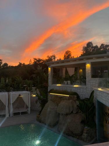 a house with a swimming pool in front of a sunset at Oasi Blu Sardinia in Santa Margherita di Pula