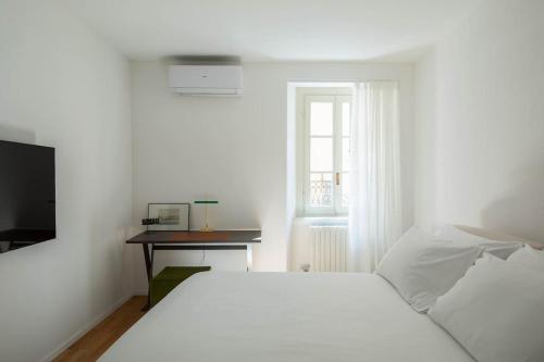 Un dormitorio blanco con una cama y un escritorio. en La Vacanza Bellagio, en Bellagio