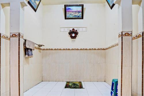 um quarto com piso em azulejo branco e uma parede em OYO 93107 Homestay H Syarif Syariah – Bandar Gresik em Gresik