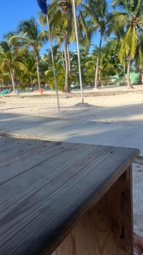 a wooden bench on a beach with palm trees at D, Altagracia casa de campo saona in La Romana
