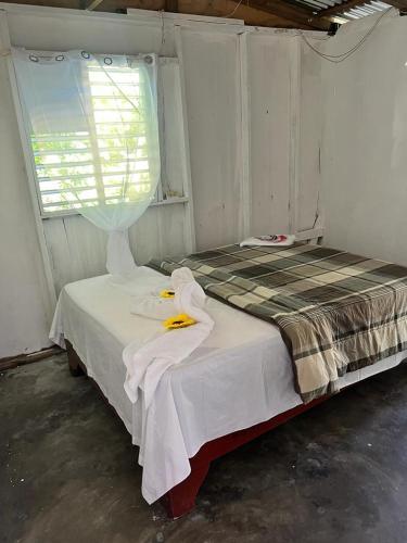 a bedroom with a bed with white sheets and a window at D, Altagracia casa de campo saona in La Romana