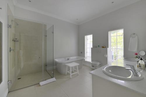 a white bathroom with a shower and a sink at Fransvliet Guest House in Franschhoek