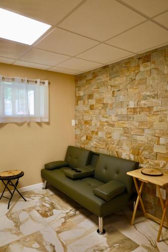 a living room with a green couch and a stone wall at Farm Country House with Pool and Huge Property in Blakeslee