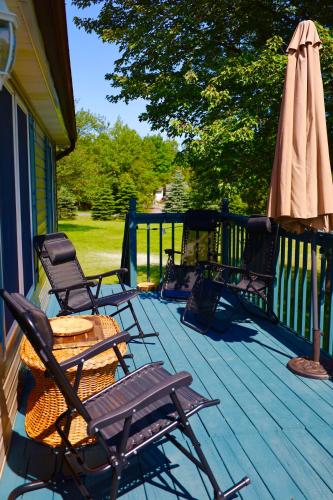 a deck with chairs and a table and an umbrella at Farm Country House with Pool and Huge Property in Blakeslee