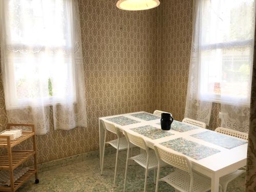 una mesa blanca y sillas en una habitación con ventanas en El Chalet Amarillo en Cabañas