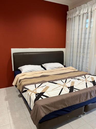 łóżko w sypialni z czerwoną ścianą w obiekcie Big Dreams Double Story House w mieście Tanah Rata