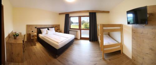 a bedroom with a bed and a tv and a window at Landgasthof Baumgartner in Dingolfing