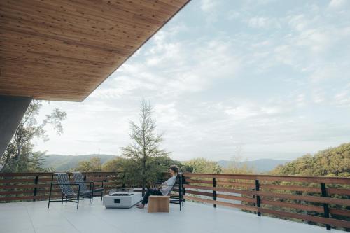 une personne assise sur une chaise sur un balcon donnant sur les montagnes dans l'établissement SOOTHE FOREST, à Shio